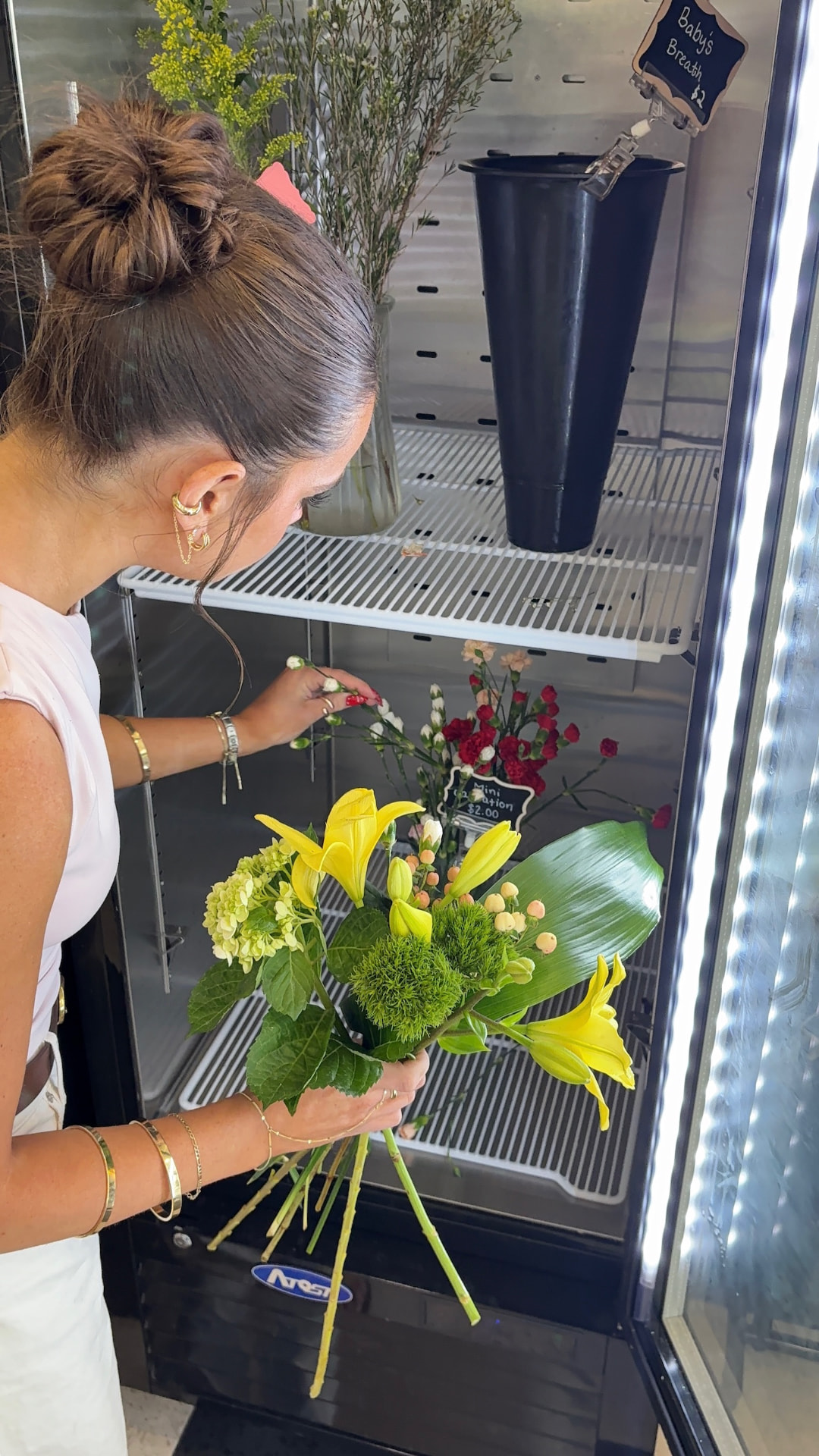 Guest gathering yellow lilies and hydrangea into a bouquet at the cooler