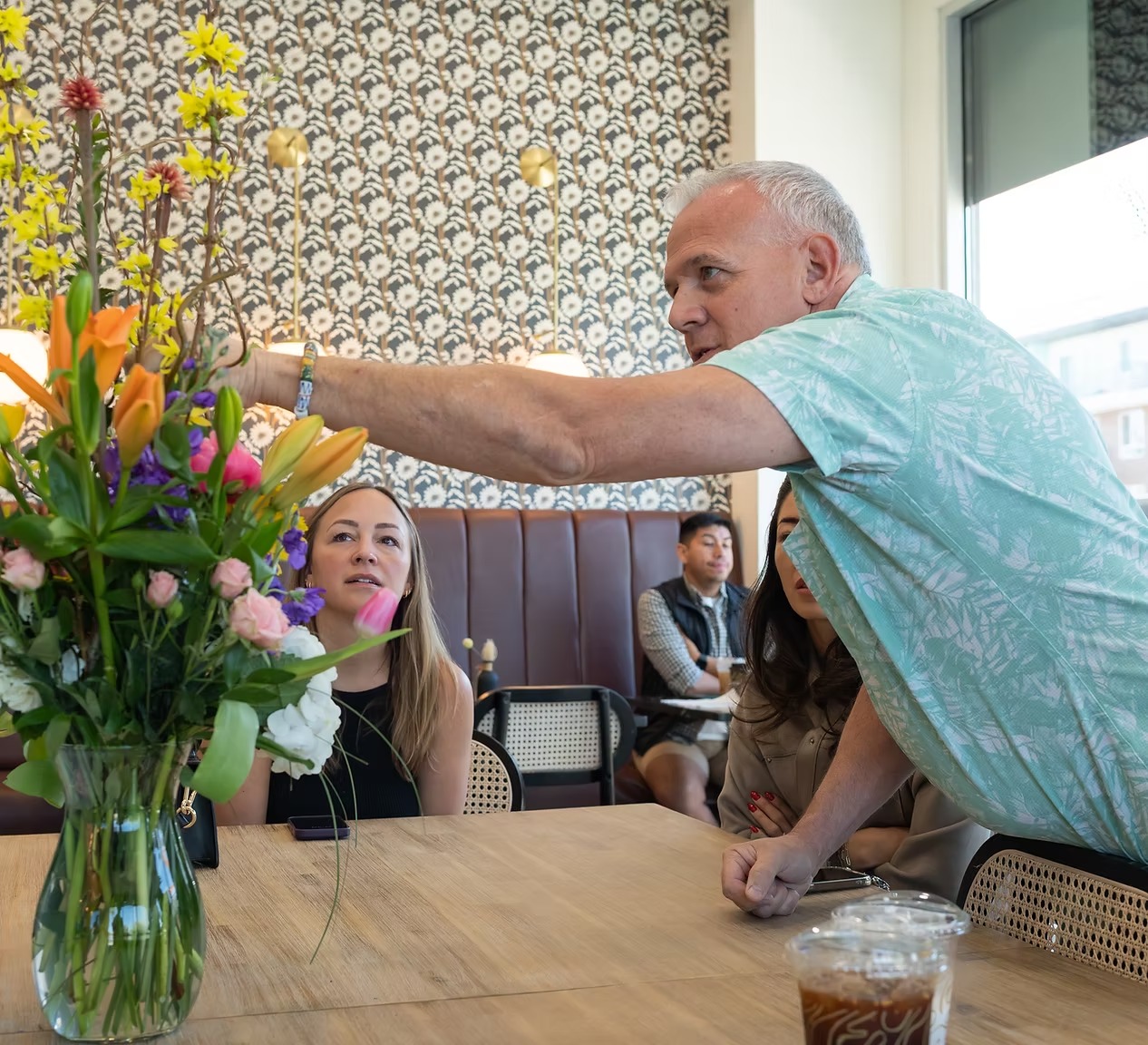 Guests laughing mid-bouquet build during a private floral class